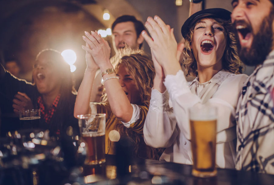 Men and women in a bar and drinking beer cheering