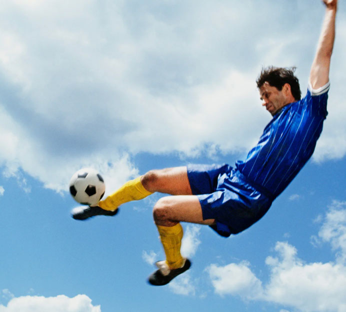 Image of a man in the air kicking a soccer ball